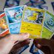 A man holds Pokemon cards for Charmandar, Squirtle, Pikachu, and Bulbasaur.